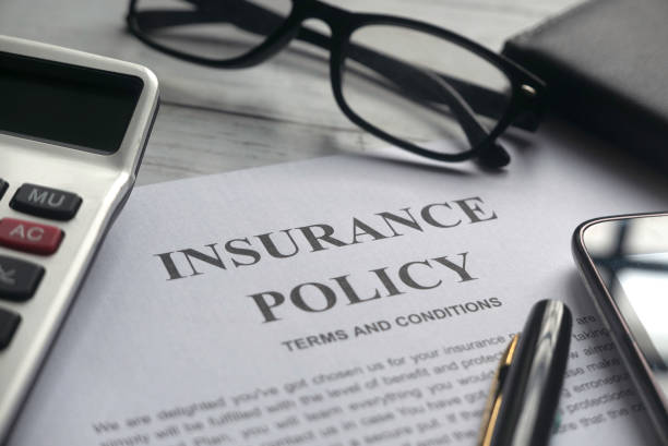 Picture of insurance policy on a desk surrounded by reading glasses, calculator, and pen.