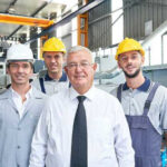 Factory owner on shop floor with 3 employees.