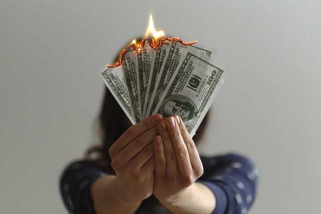 Woman holding paper money in flames